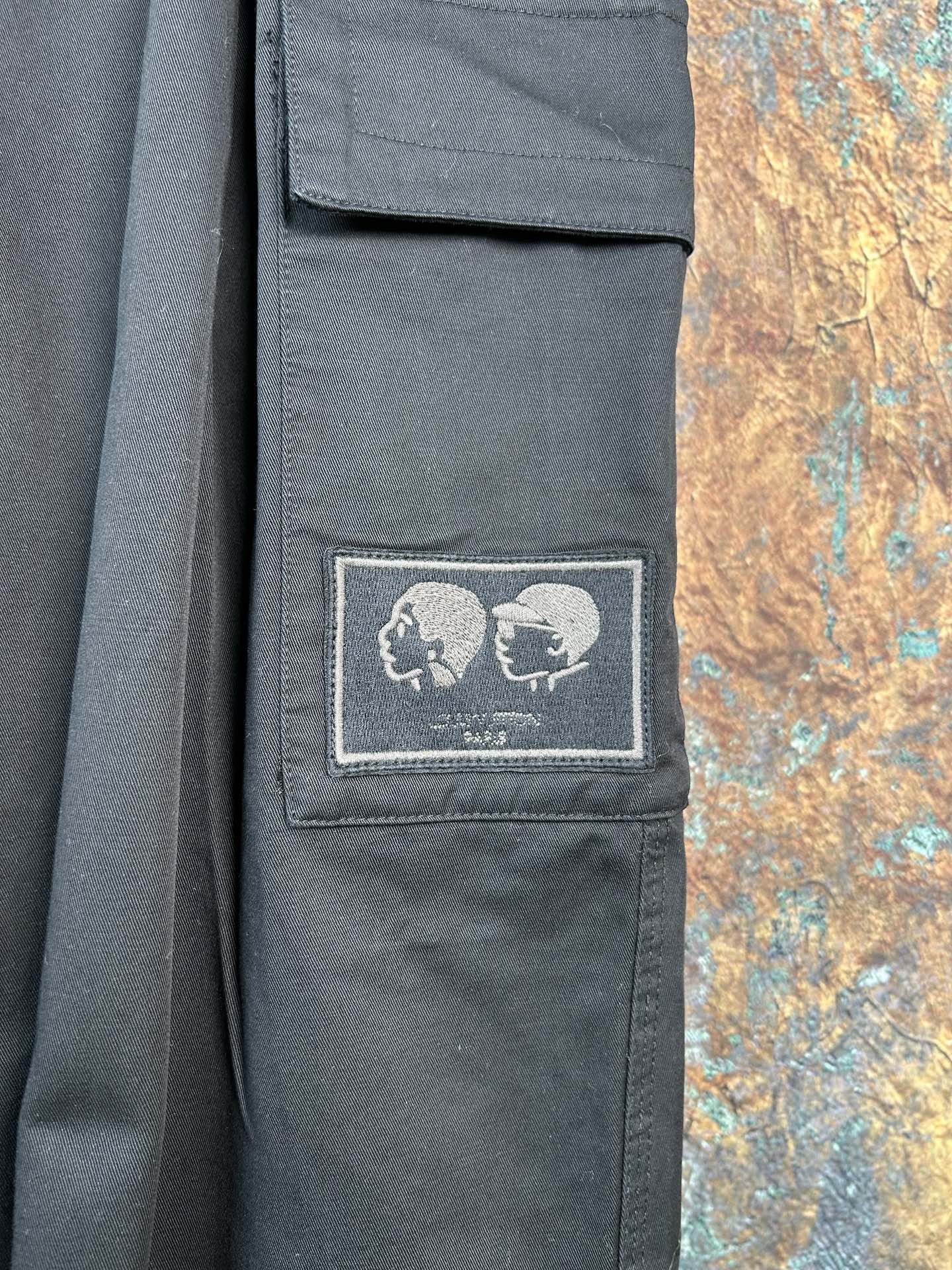 Black cargo pants with embroidered skull patch on a thigh pocket