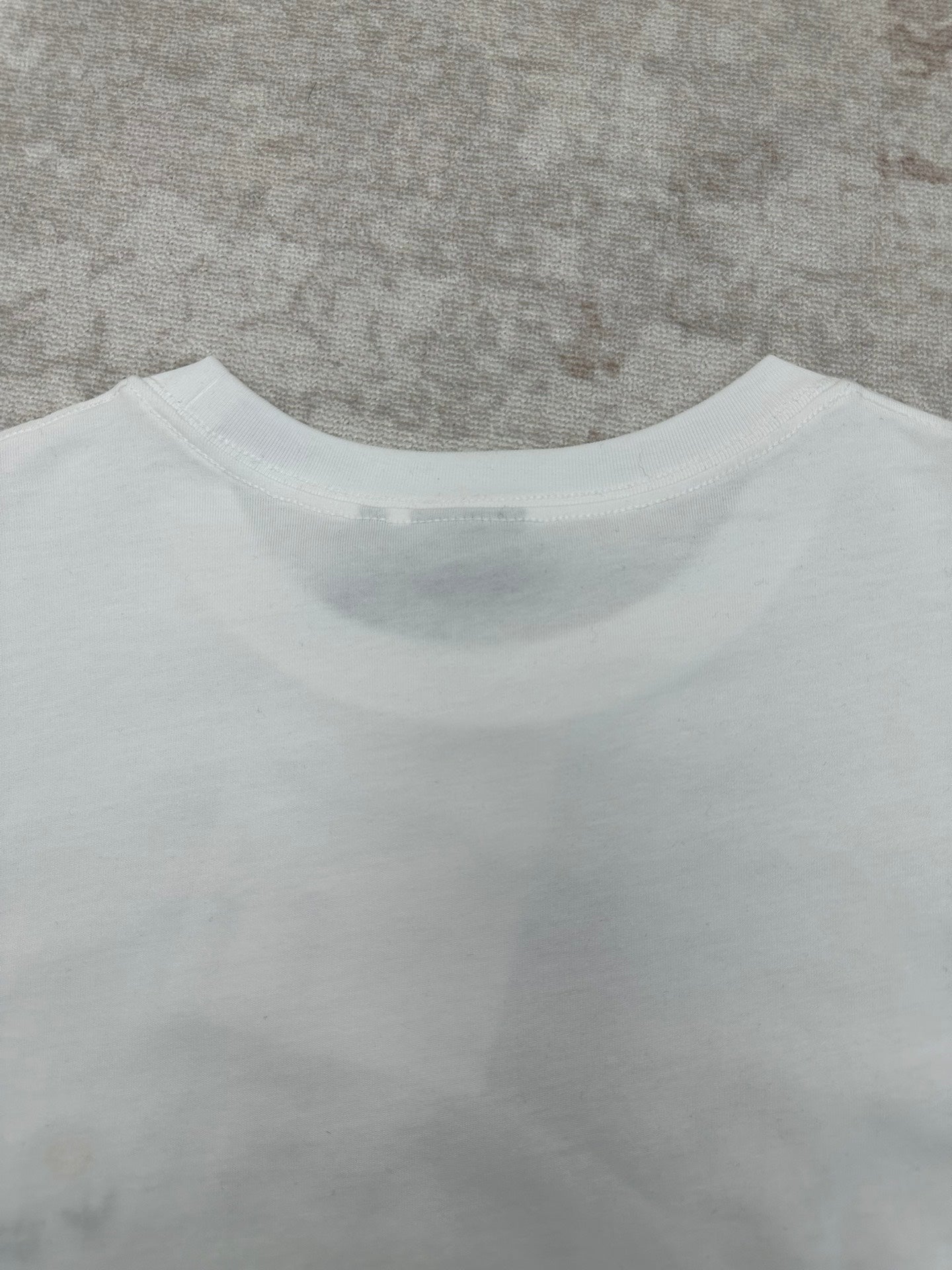 White T-shirt back neckline and upper back seam detail.