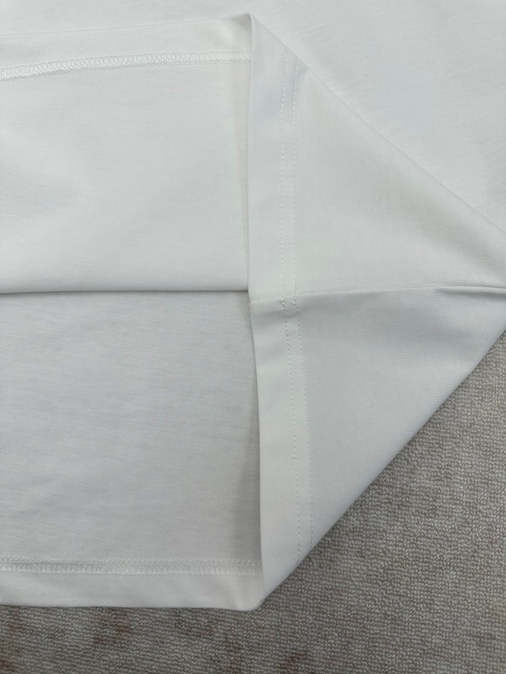 White T-shirt hem and side seam with stitching detail.