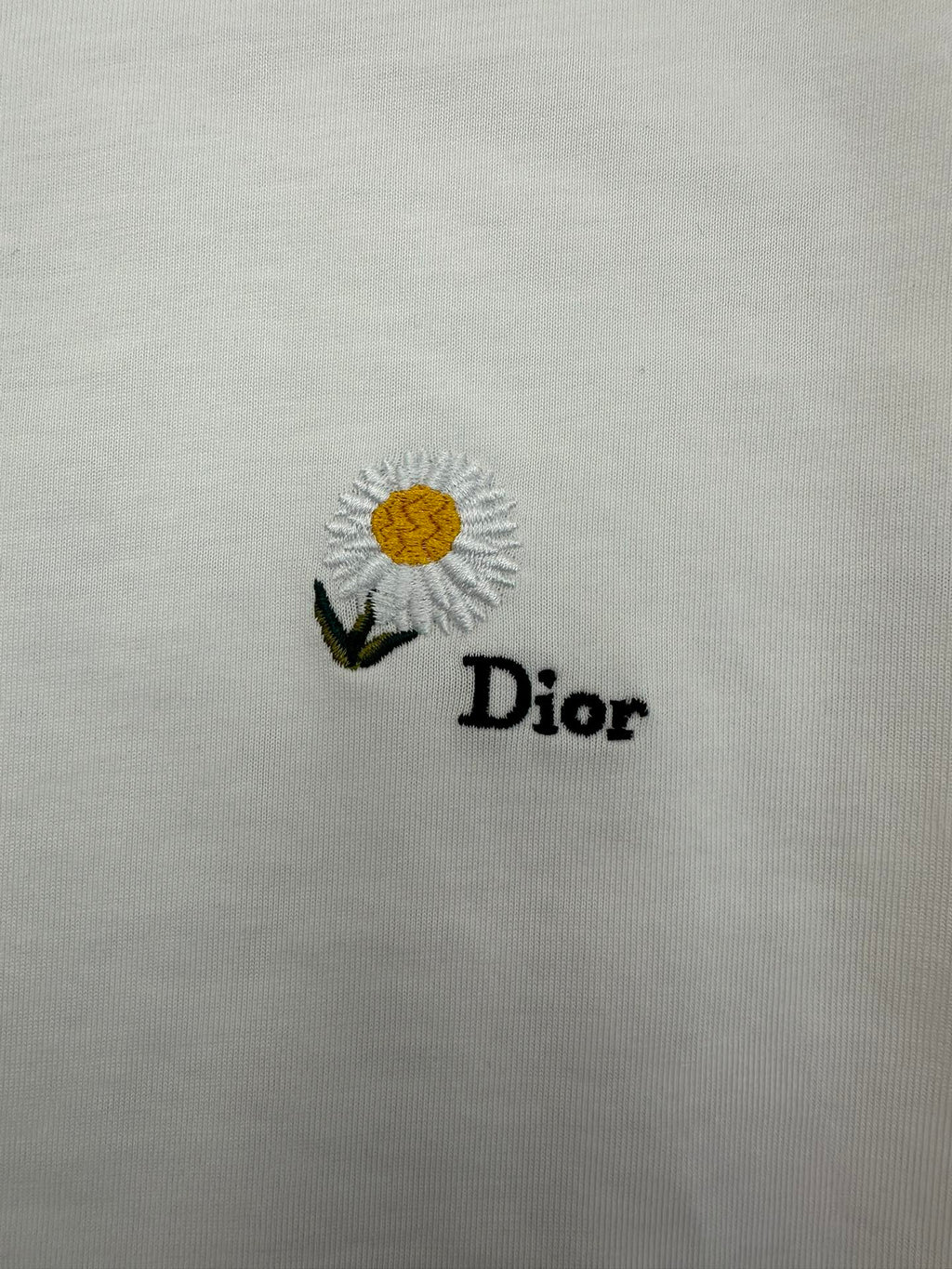 White T-shirt with daisy embroidery and "Dior" text logo on front.