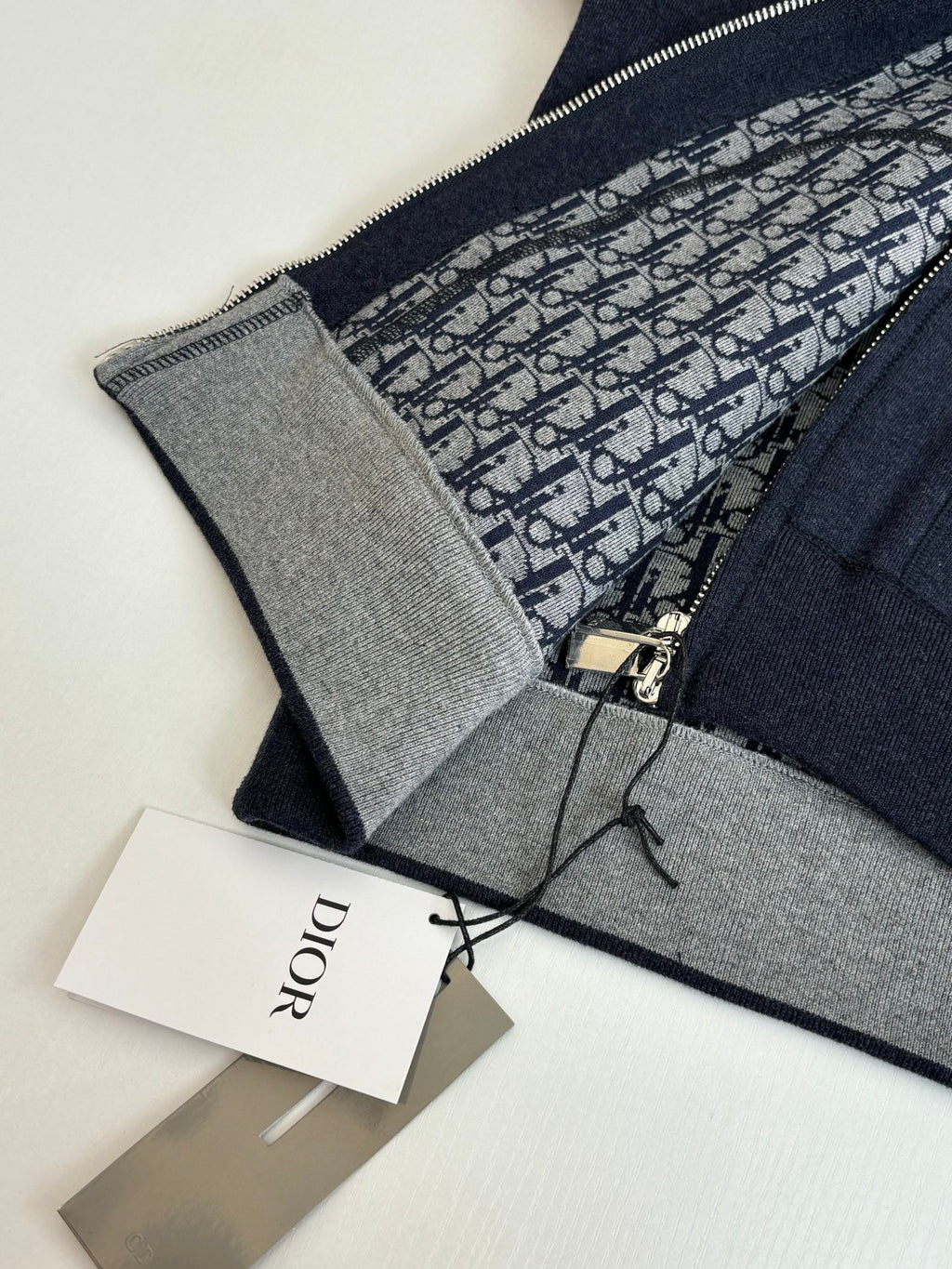 Dior hoodie close-up: patterned lining, zipper pull, and gray inner trim