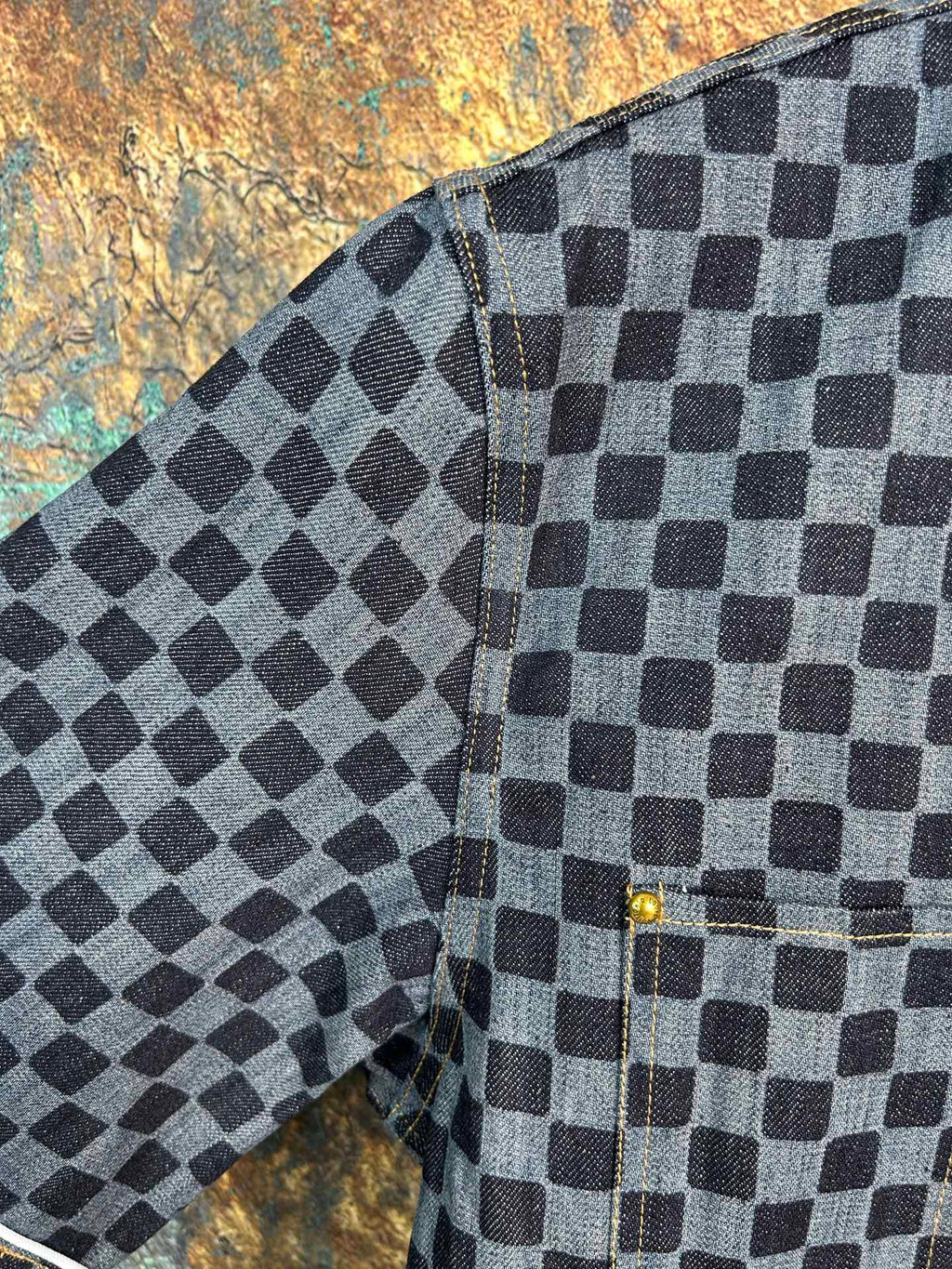 Checkered shirt sleeve and side seam detail with cuff stitching and dark buttons