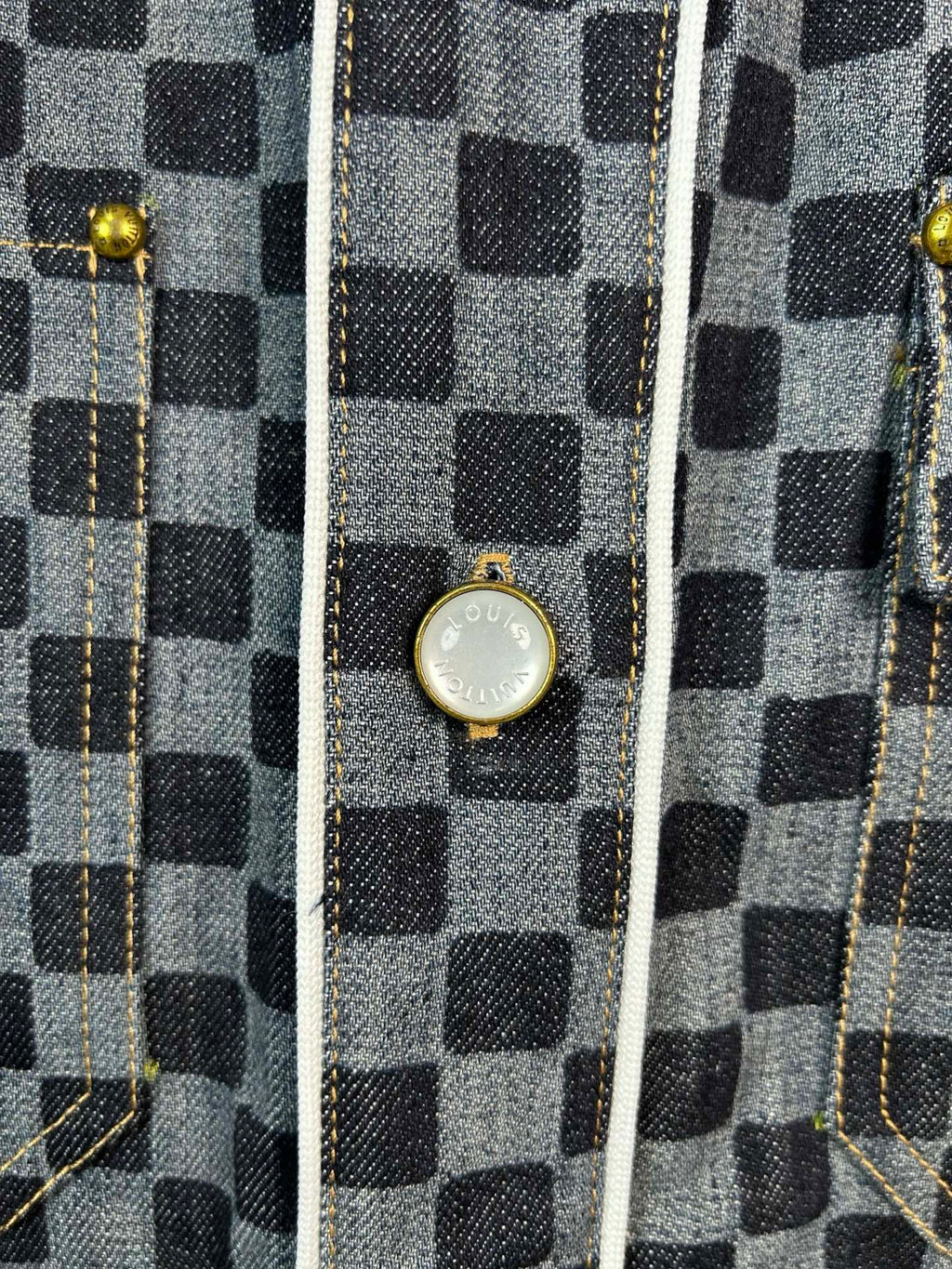 Close-up of checkered shirt front with gold-tone snap buttons and trim seams