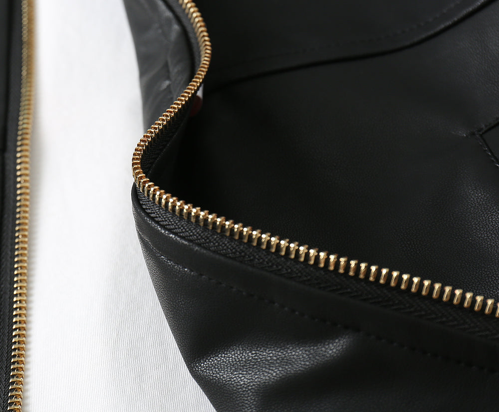 Close-up of black leather jacket zipper with gold-tone teeth and stitching