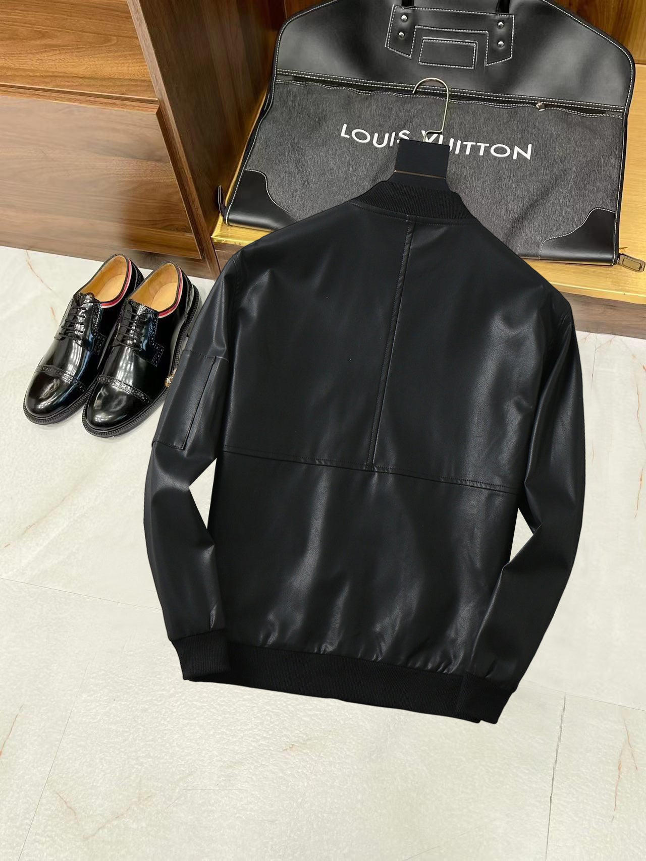 Black leather jacket back view with structured shoulders and stand collar