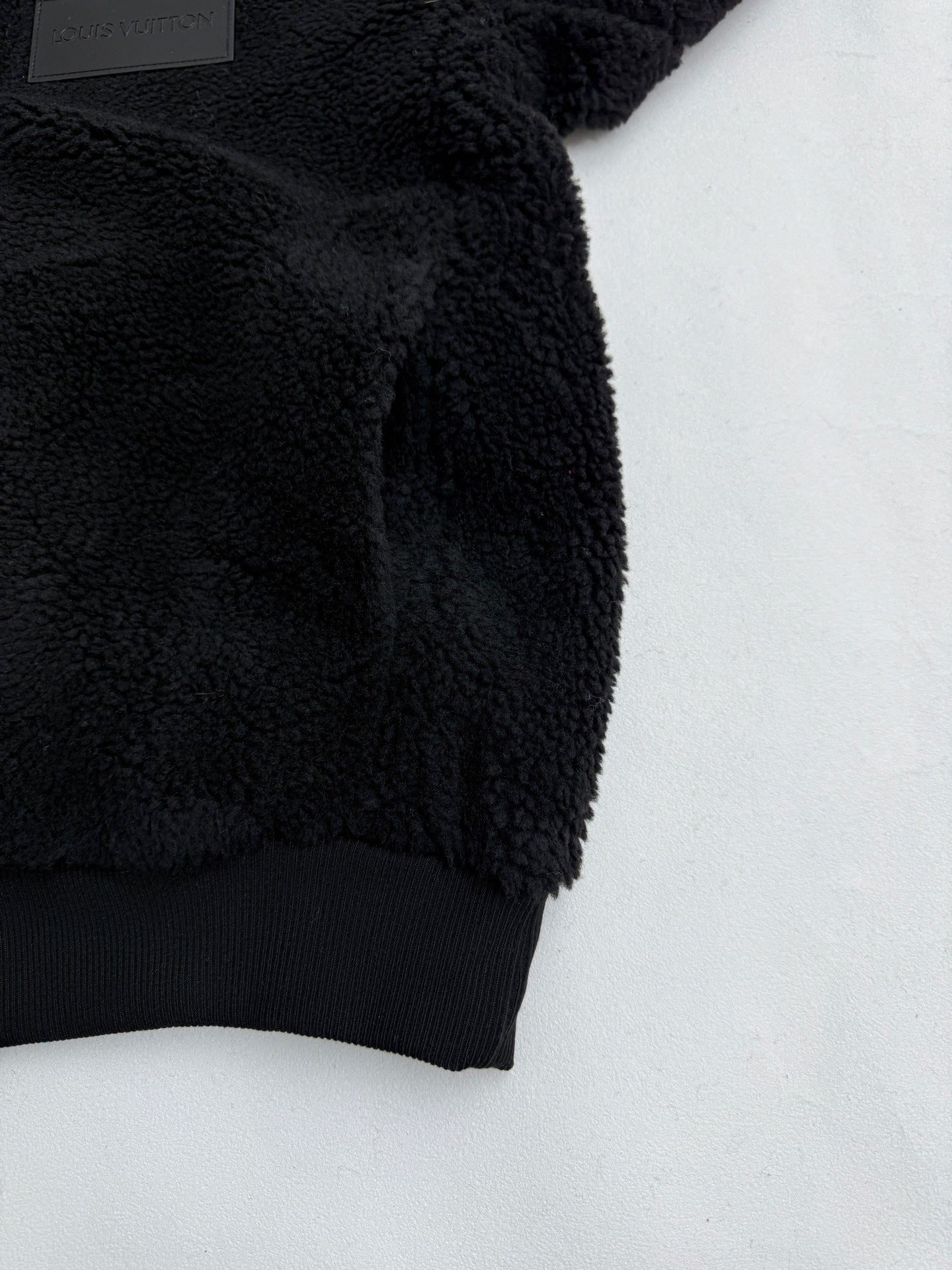 Black sherpa jacket sleeve with ribbed hem and embroidered cuff