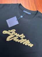 Louis Vuitton black T-shirt with gold embroidered script logo and attached product tag