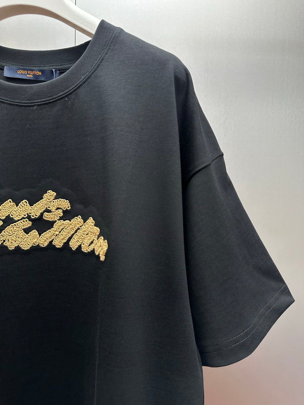Louis Vuitton black T-shirt with gold embroidered script logo detail, short sleeve close-up