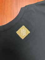 Louis Vuitton black crewneck T-shirt with small gold logo patch at the collar