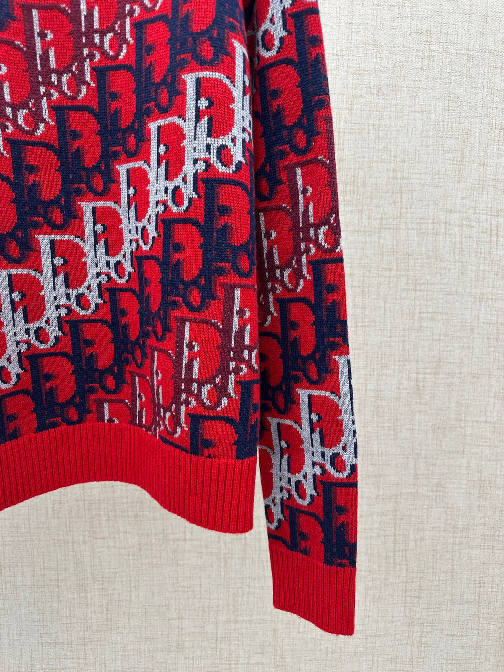 Dior knit sweater side view: red and navy logo knit with ribbed hem detail