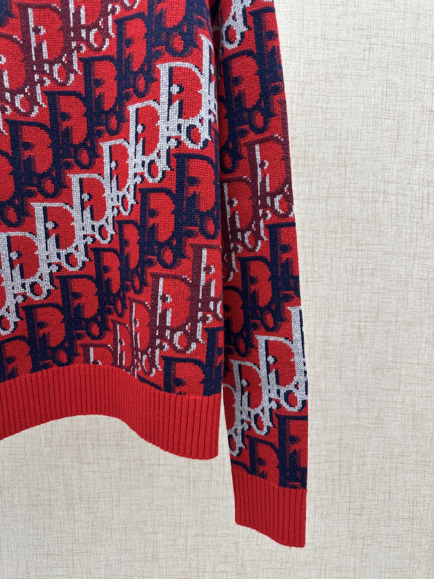 Dior knit sweater side view: red and navy logo knit with ribbed hem detail