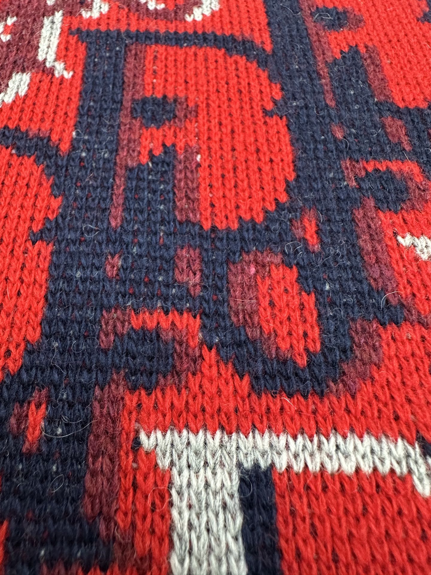Dior knit fabric close-up: red, navy, and white logo pattern with ribbed edge