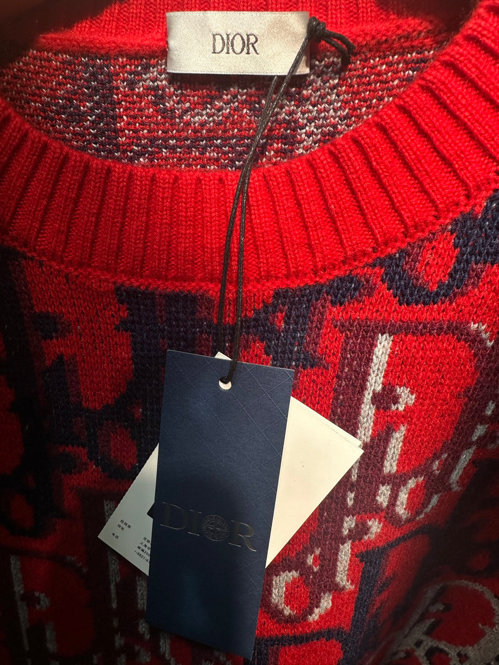 Dior knit sweater close-up: red, navy, and white logo knit with ribbed trim