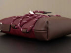Burgundy bag with brown leather base, braided drawstring ties, and silver hardware
