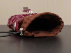 Burgundy bag opening with brown inner lining, snap hardware, and drawstring cord