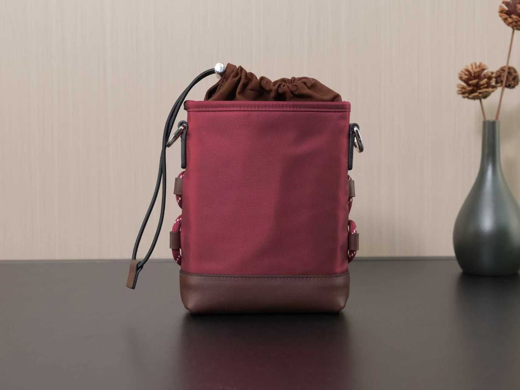 Burgundy drawstring bucket bag with side handles and adjustable shoulder strap