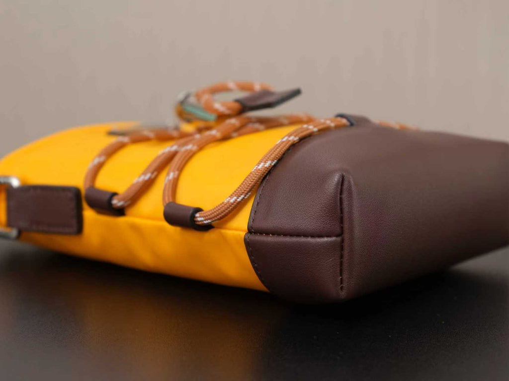 Yellow and brown Prada bag with braided strap and rounded brown side panel.