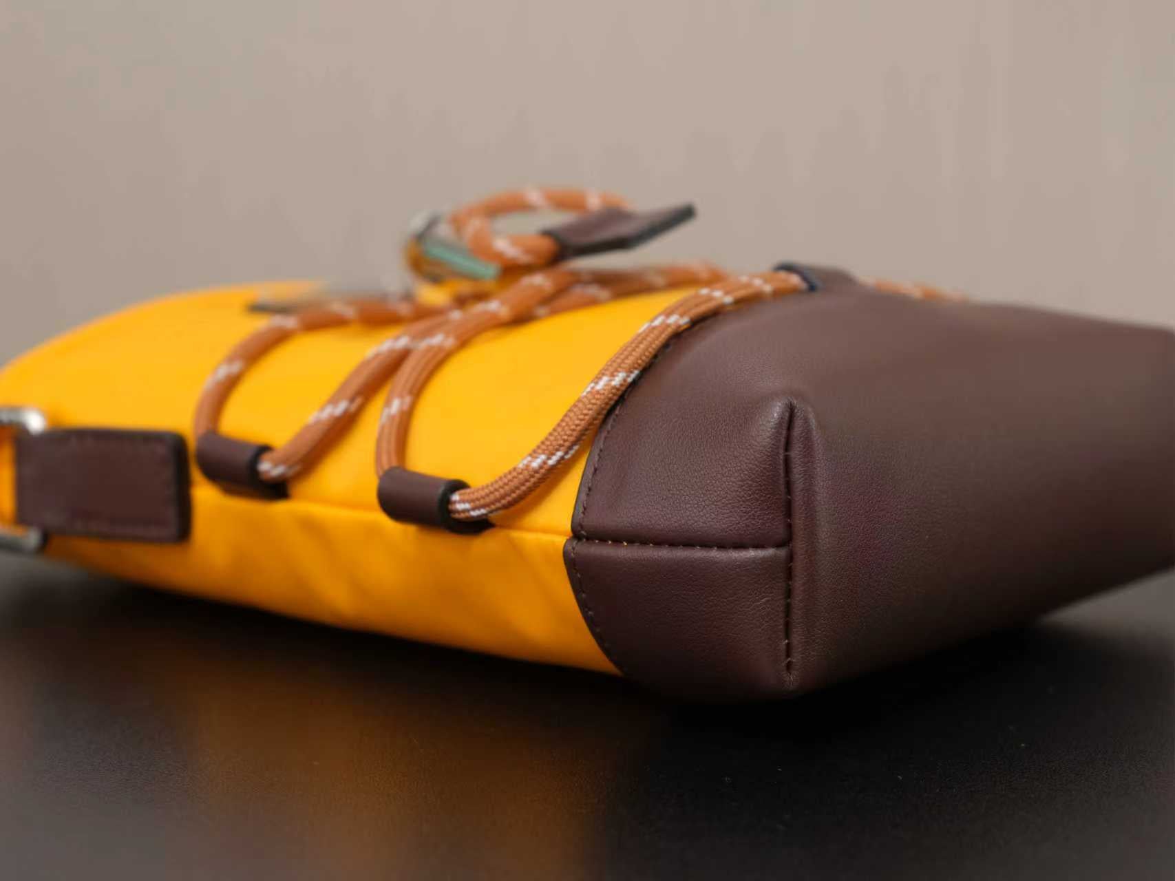 Yellow and brown Prada bag with braided strap and rounded brown side panel.