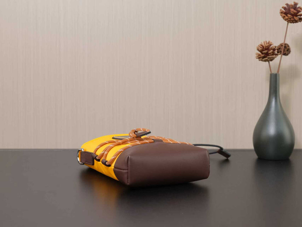 Prada bag with yellow body and brown side pocket, lying on its side.