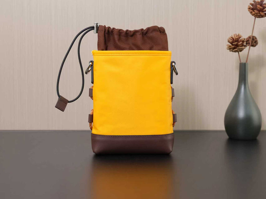 Yellow Prada bucket-style bag with brown base and drawstring closure.