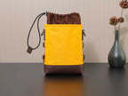 Yellow Prada bucket-style bag with brown base and drawstring closure.