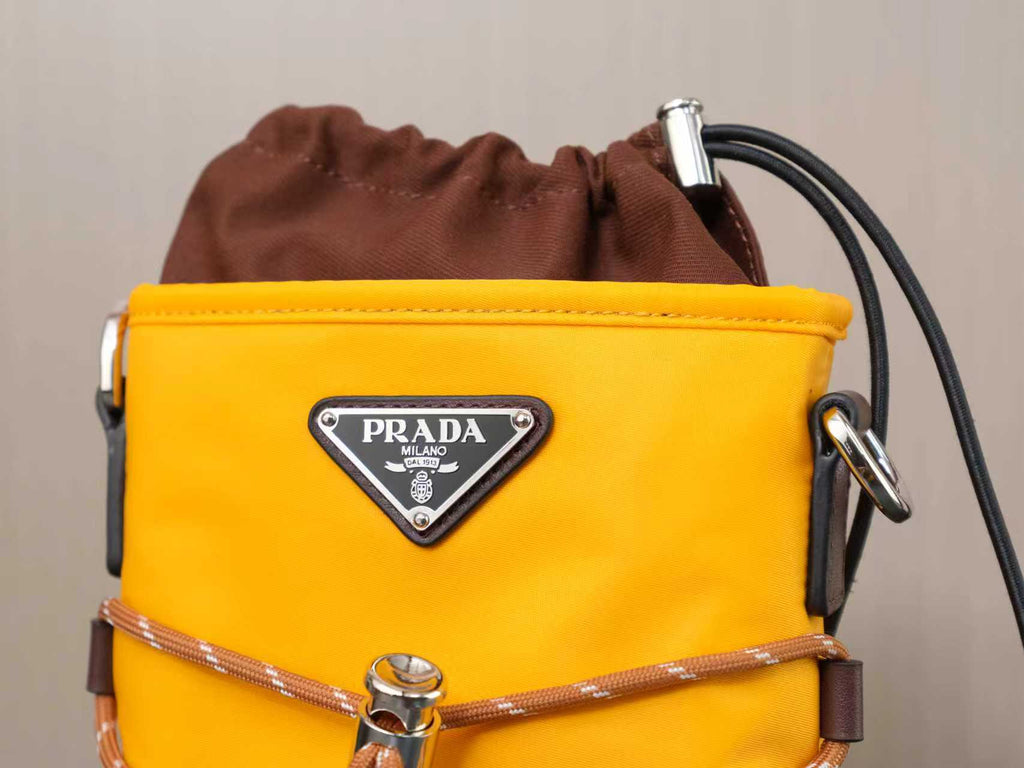 Yellow Prada bag close-up with brown drawstring, silver hardware, and logo triangle.