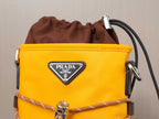 Yellow Prada bag close-up with brown drawstring, silver hardware, and logo triangle.