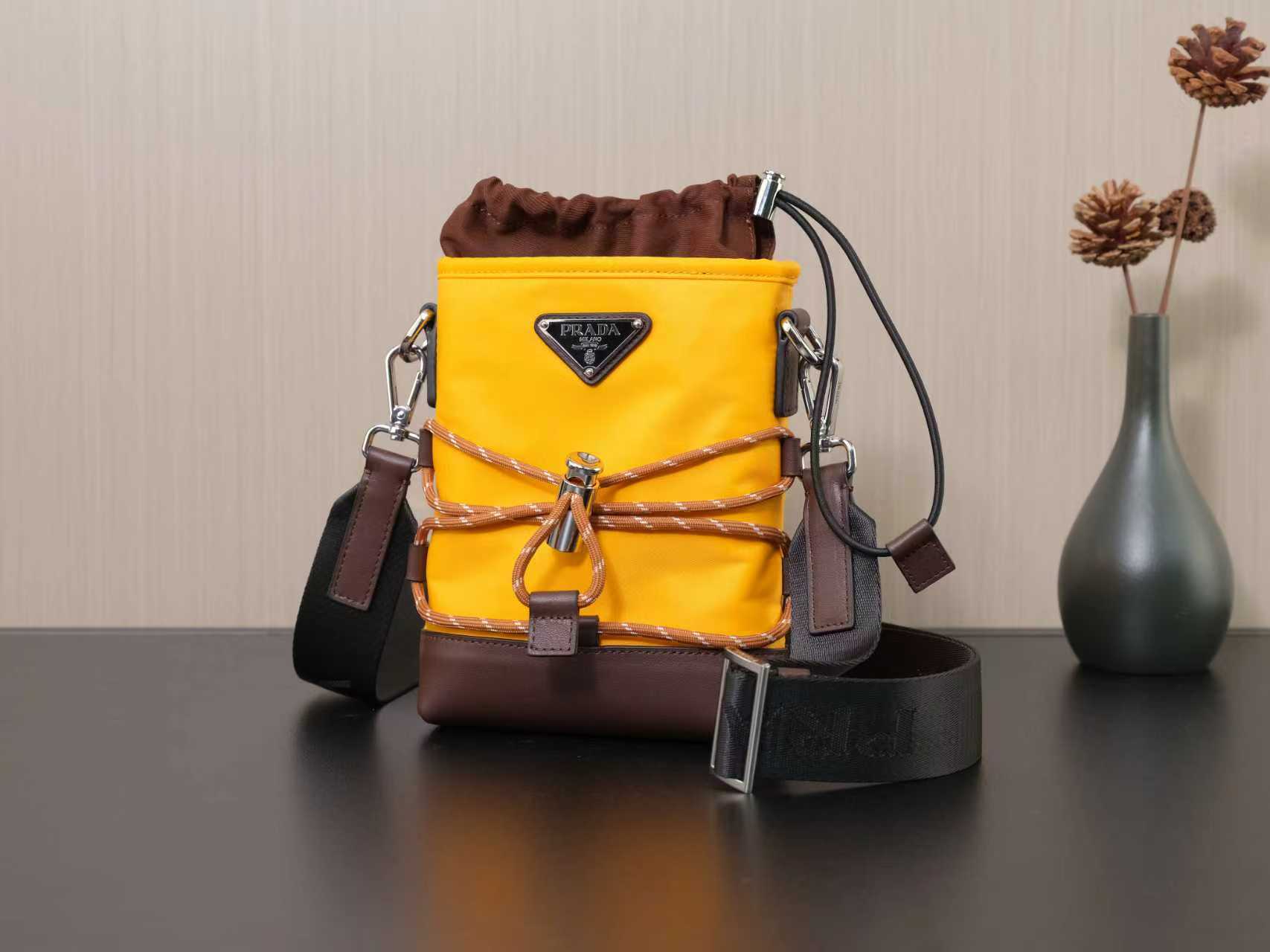 Yellow Prada bag with brown drawstring top and metal logo plaque.