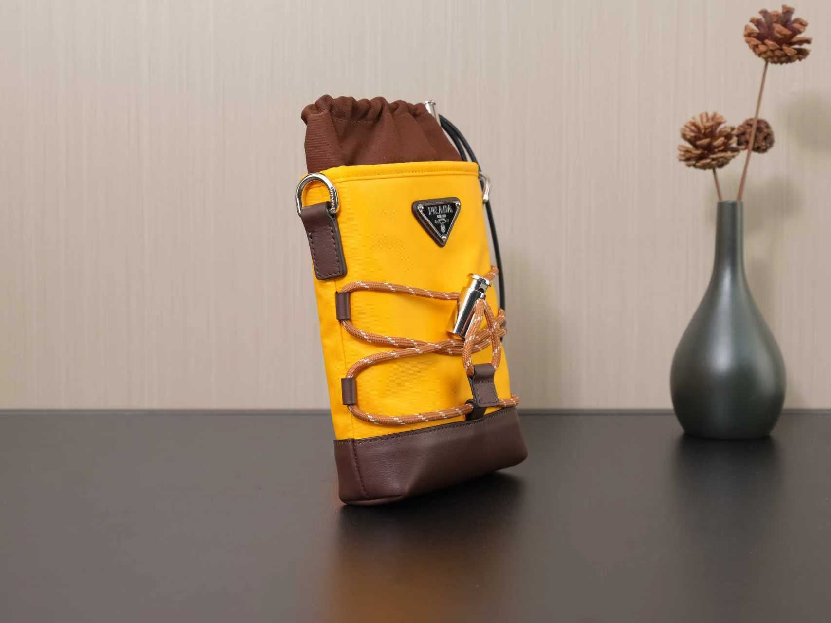Standing Prada bag in yellow with brown straps, buckle detail, and logo patch.