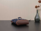 Prada bag with dark blue and brown body, shown from the side with braided strap trim