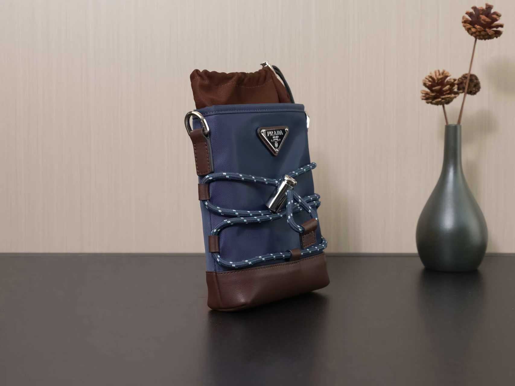 Prada mini crossbody bag in dark blue with brown bottom and triangular front logo