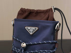 Prada shoulder bag front view with dark blue flap, brown top drawstring, and logo plaque