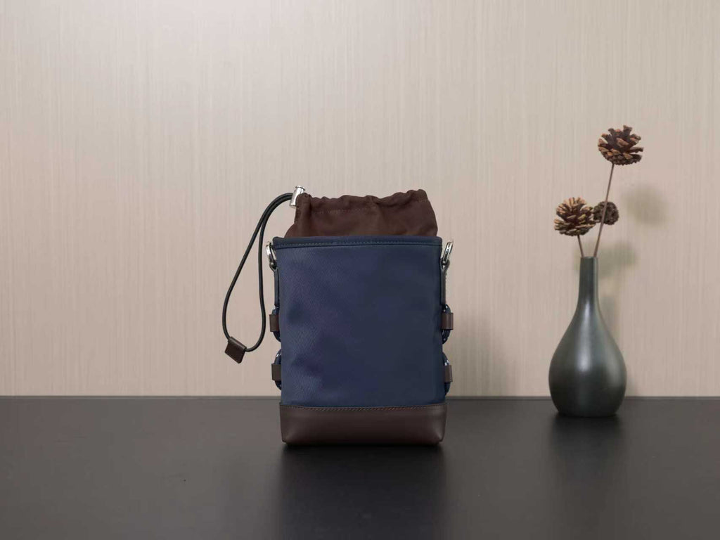 Prada mini crossbody bag with dark blue front panel, brown base, and short top handle