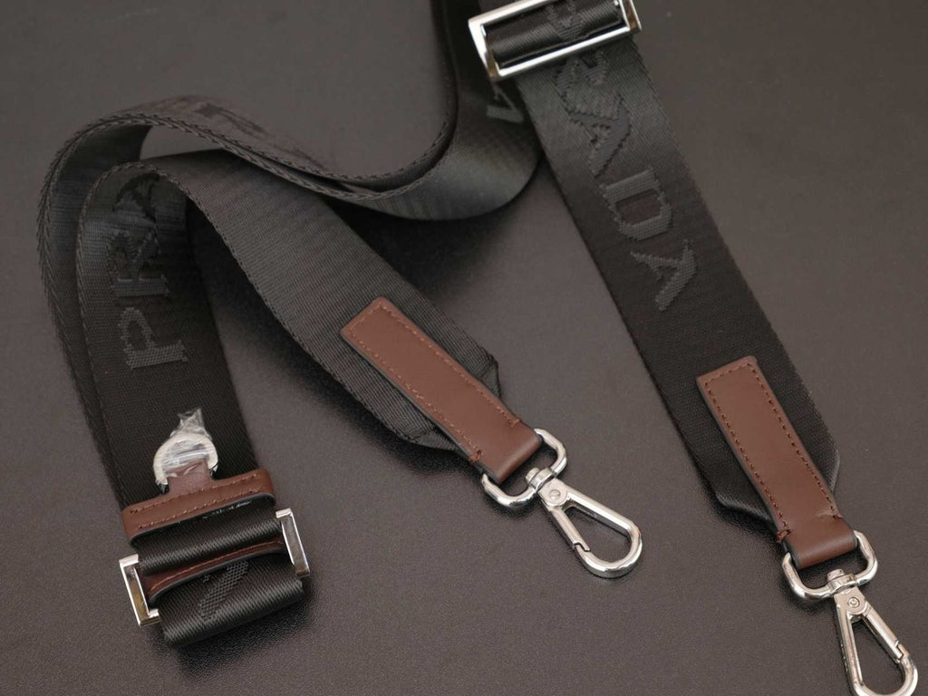 Prada bag strap set with brown leather tabs and silver metal hardware, detail view