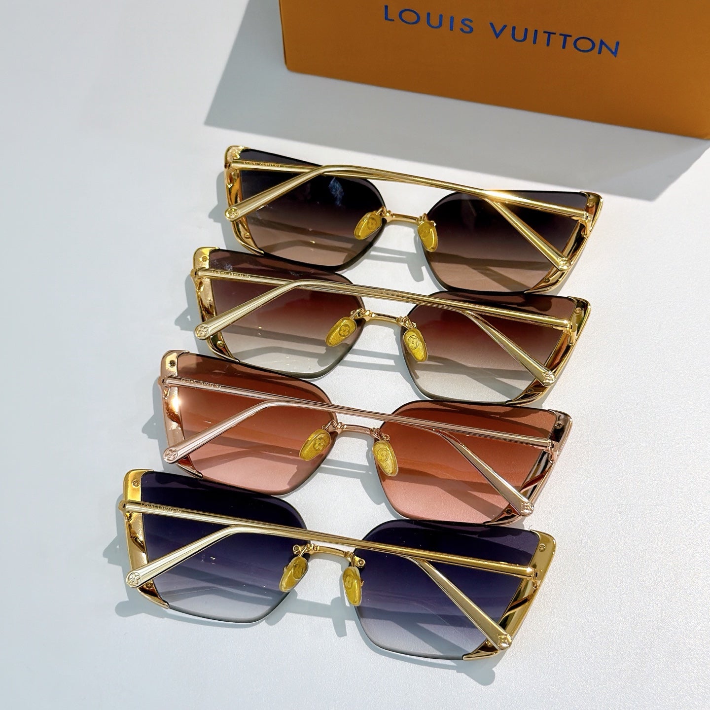 Stack of multiple Louis Vuitton sunglasses with gold frames and tinted gradient lenses