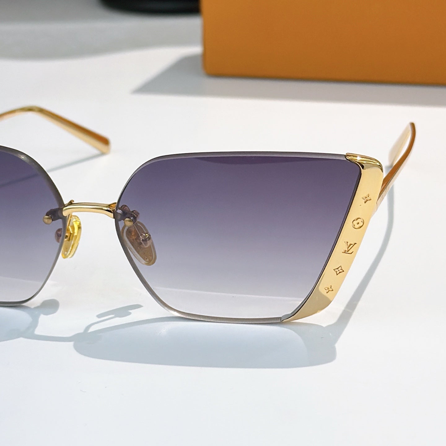 Close-up of gold-tone Louis Vuitton sunglasses with gradient purple lenses and temples