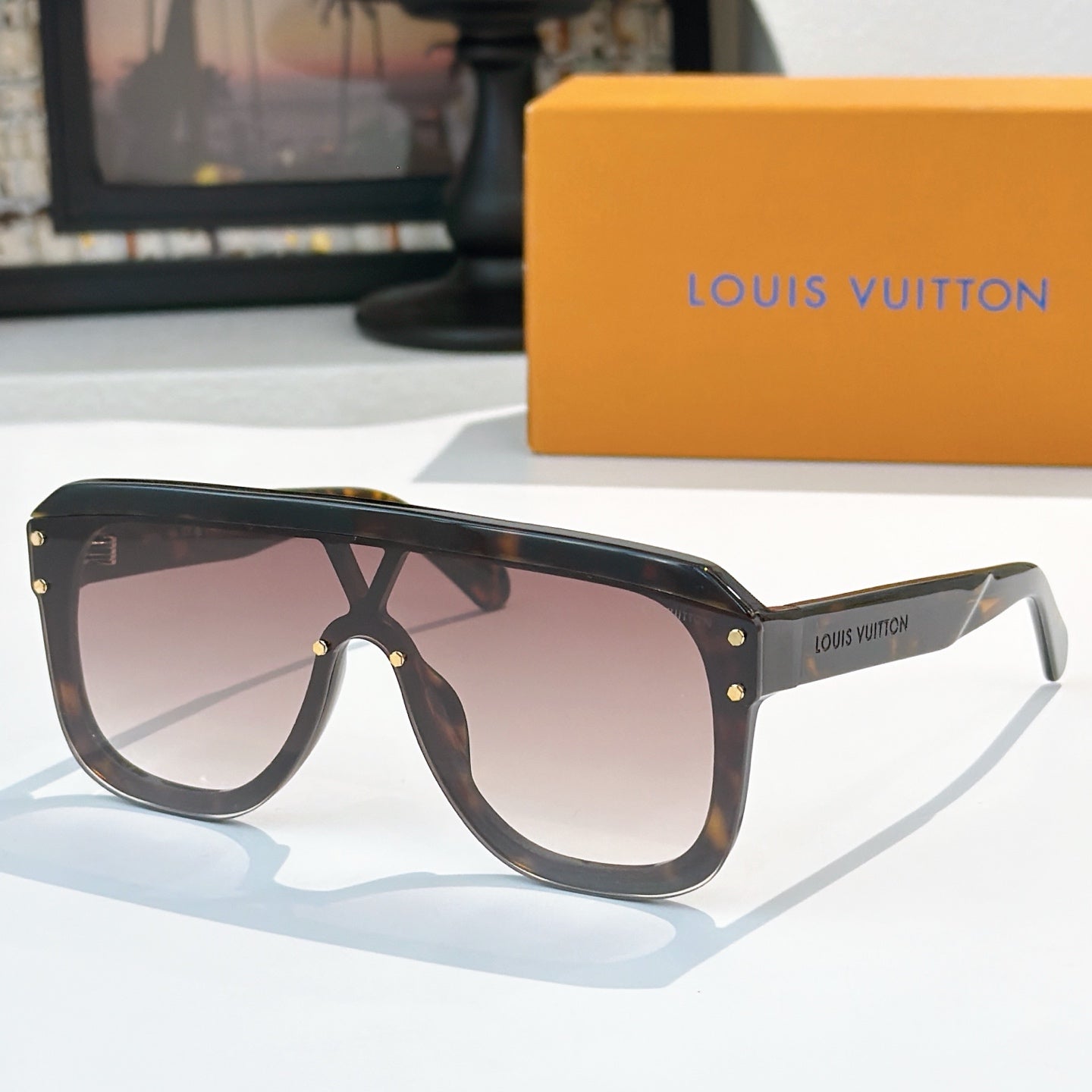 Brown sunglasses with dark lenses, gold-tone rivets, and slim arms