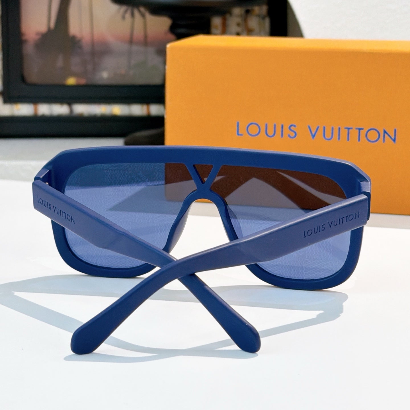 Blue sunglasses with wide lenses and cross-style temple arms