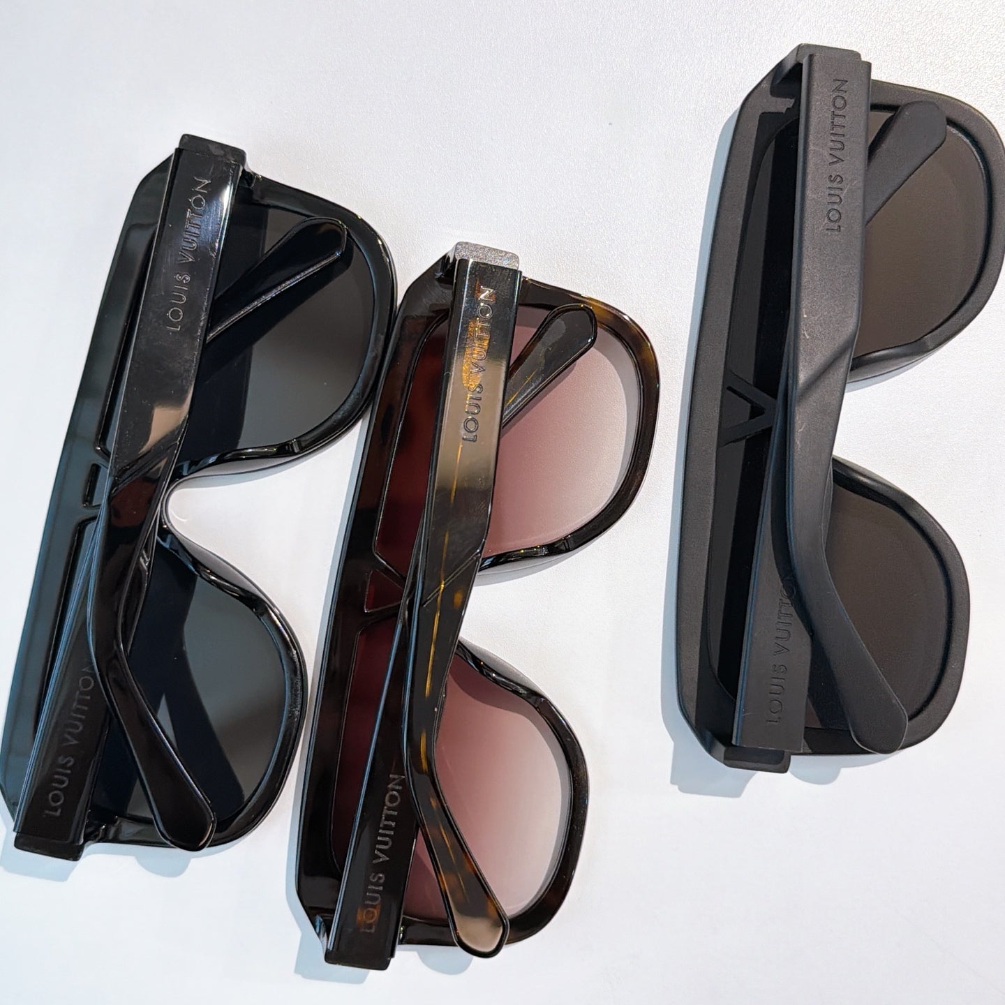 Assorted black and tortoiseshell sunglasses with tinted lenses and cases