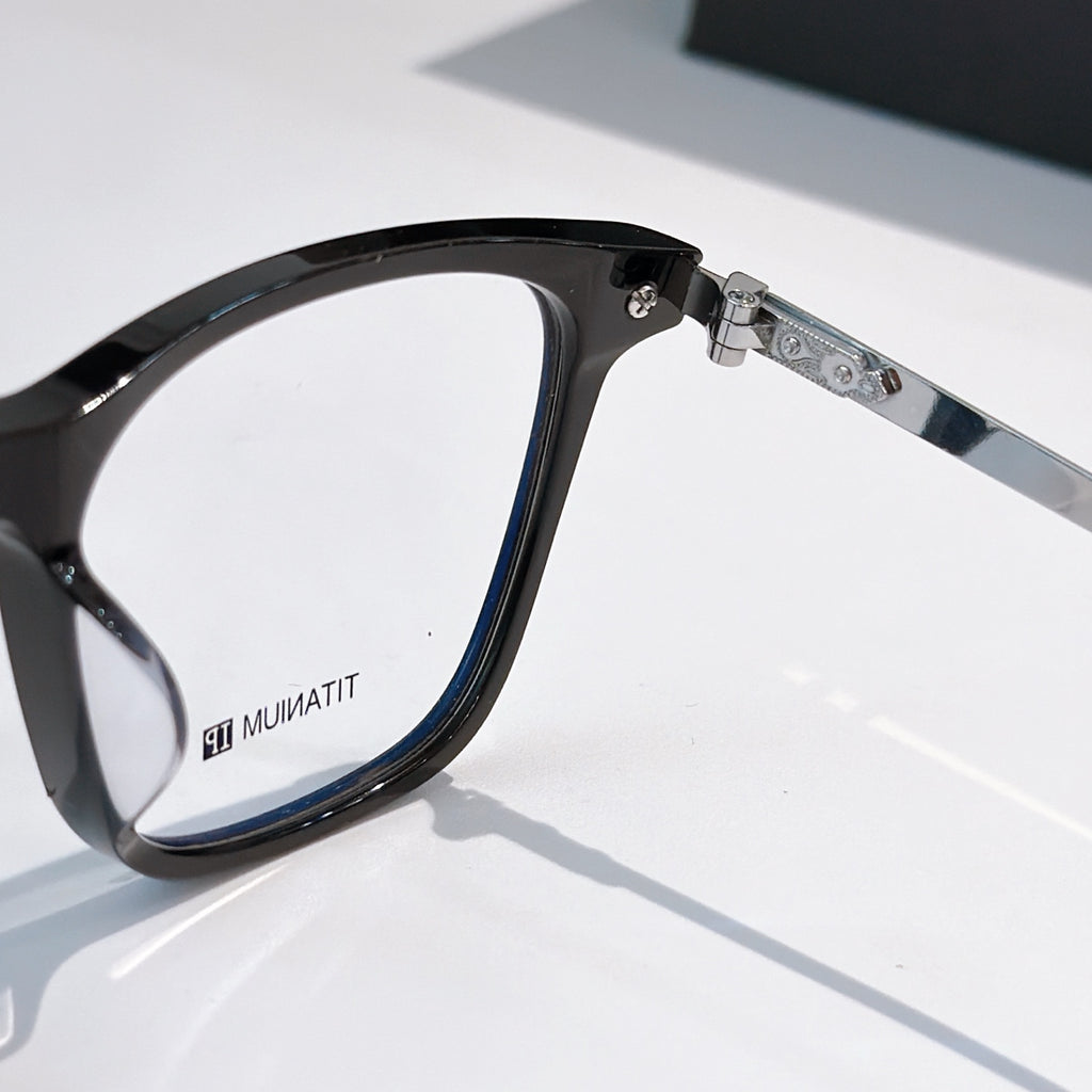 Black eyeglass frame with metal hinge and clear lenses, side view.