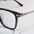Black eyeglass frame with metal hinge detail and clear lenses.