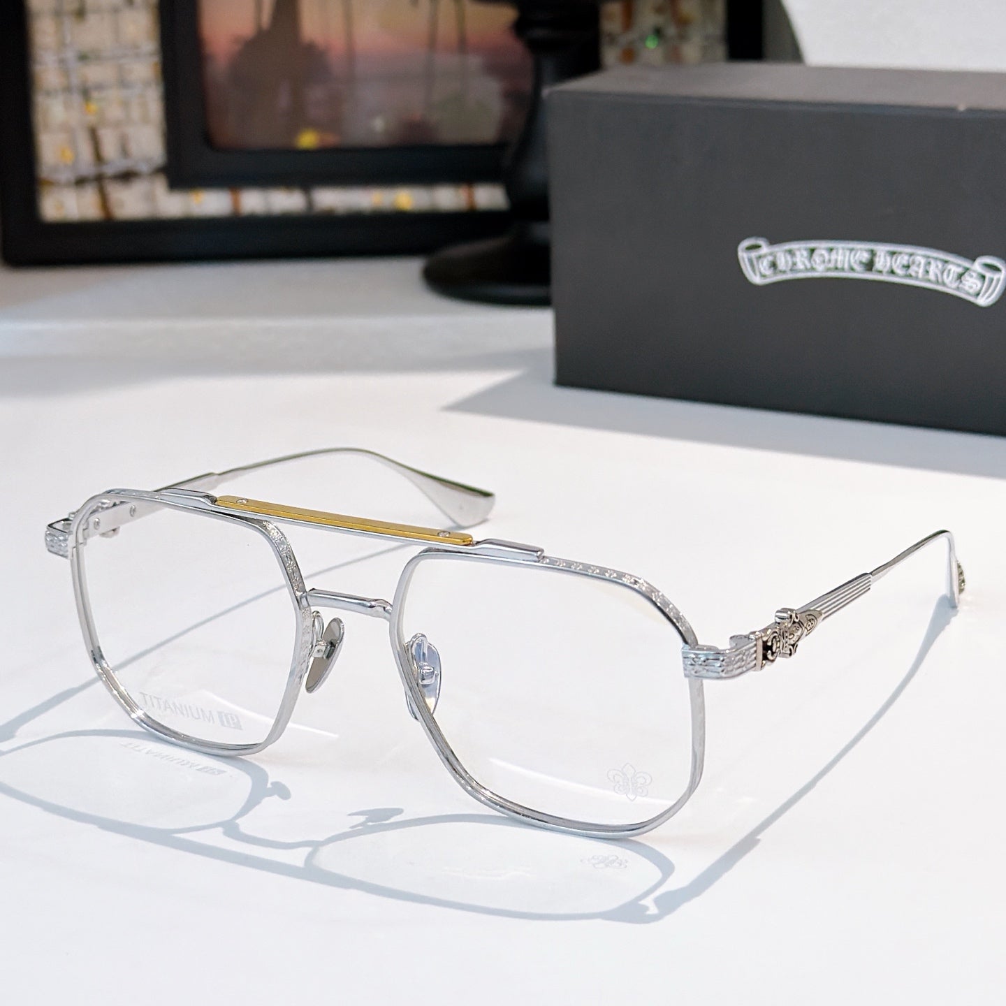 Silver-tone eyeglasses with clear lenses, thin metal frame, textured temple detail.