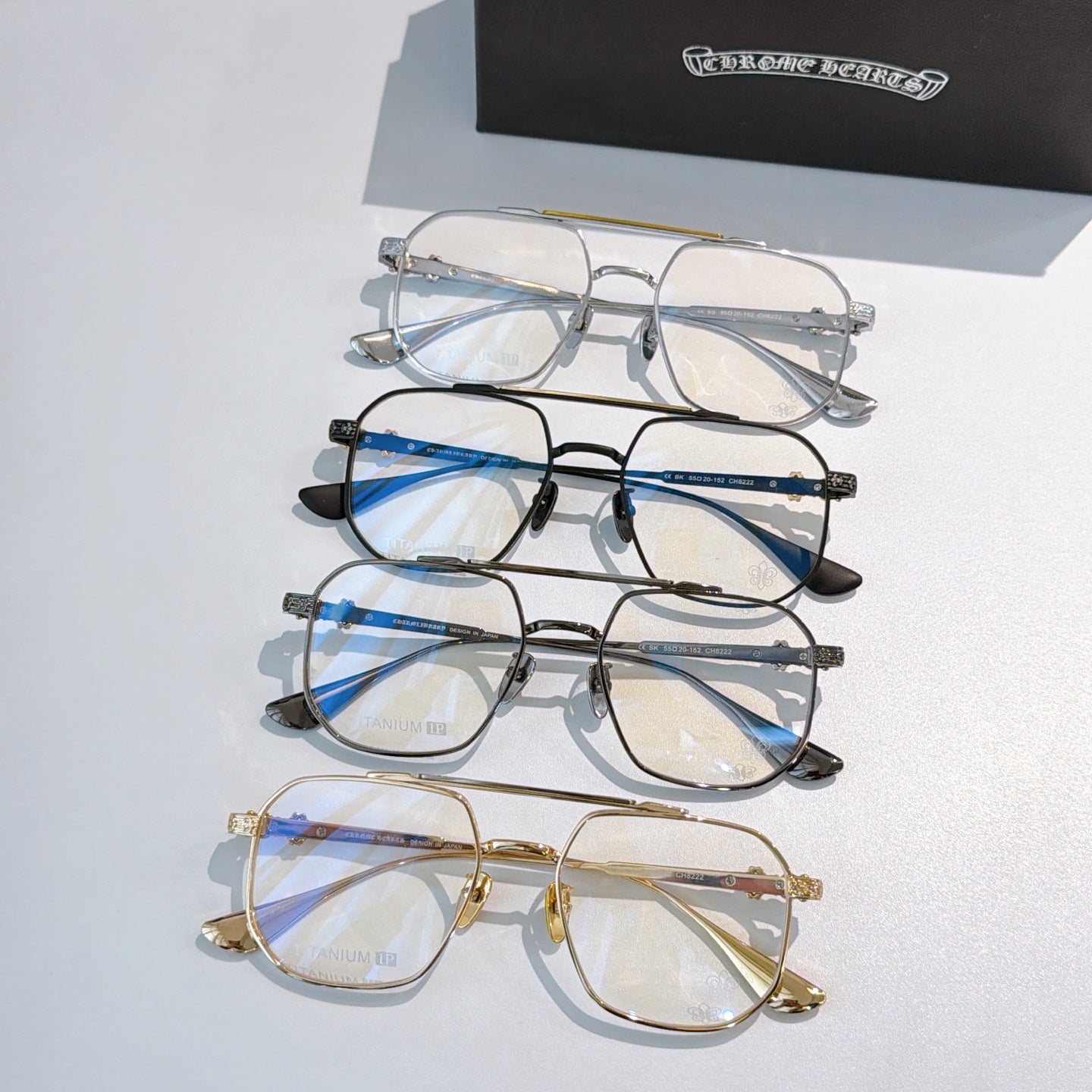 Stacked eyeglasses set with clear lenses in blue, black, and gold frames.