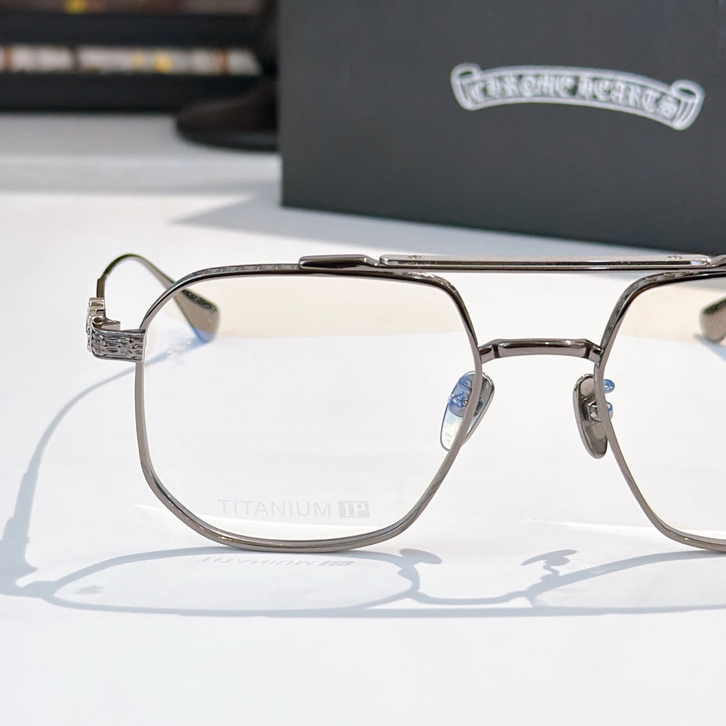 Metal eyeglass frame with clear lenses, embossed temple arms and bridge detail.