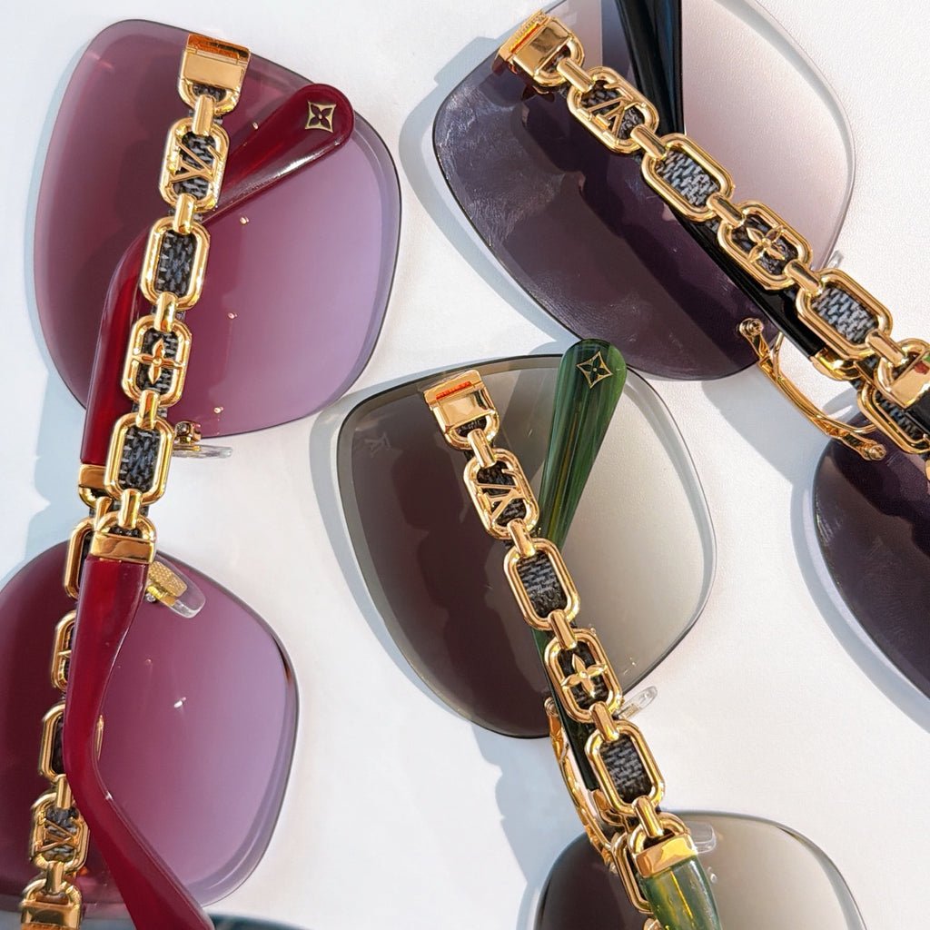 Designer sunglasses detail view with gold chain accents on purple lenses
