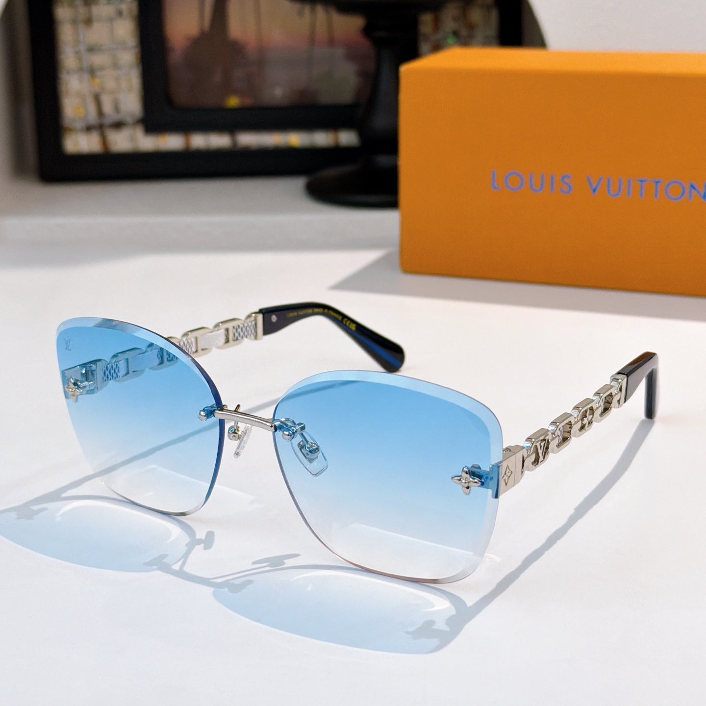 Designer sunglasses with light blue gradient lenses and gold link temples