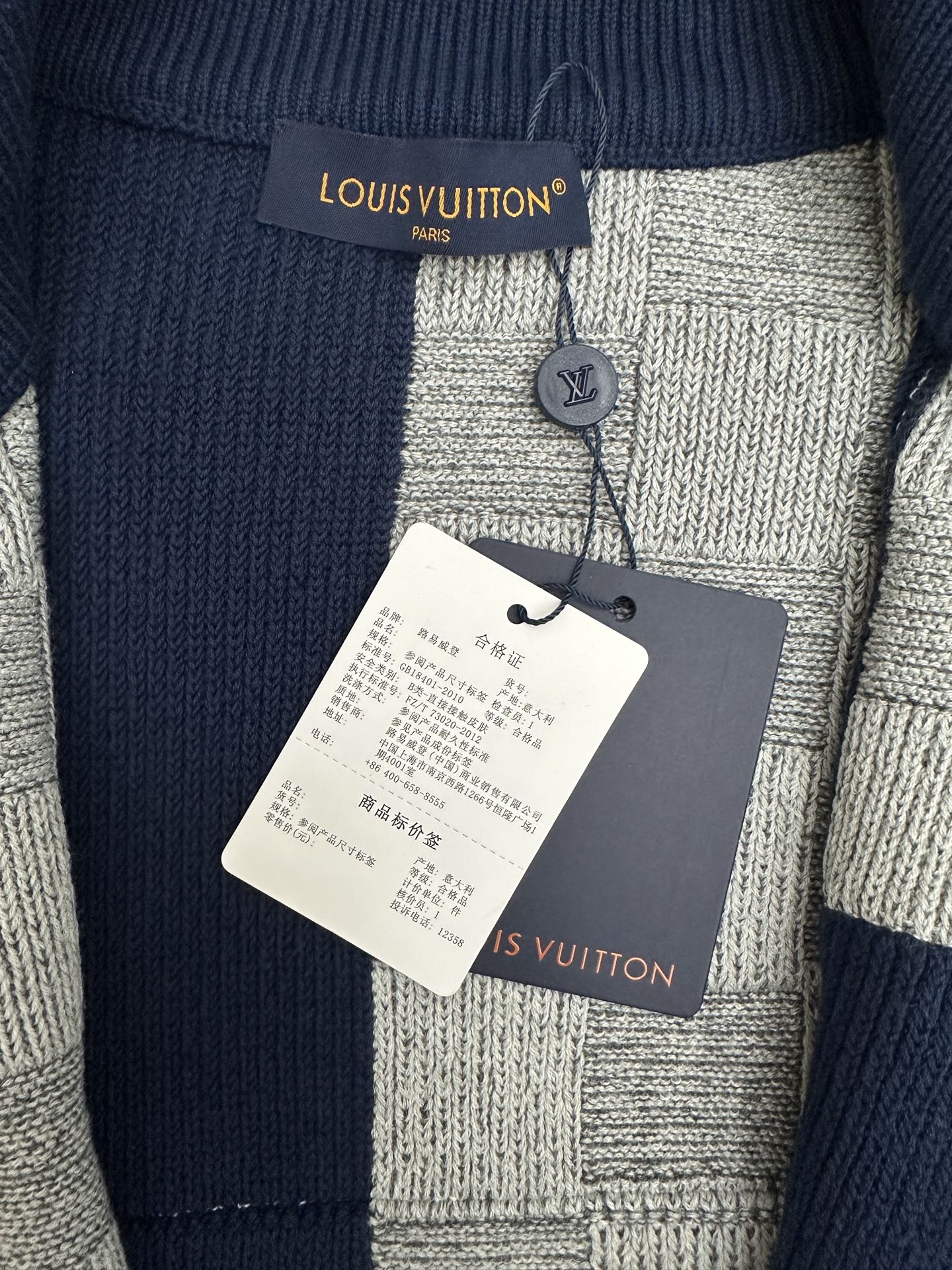 Close-up of knit collar and label on navy-and-gray patchwork zip sweater