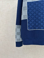 Side view of navy knit sweater jacket with textured blue panel and gray checkered band