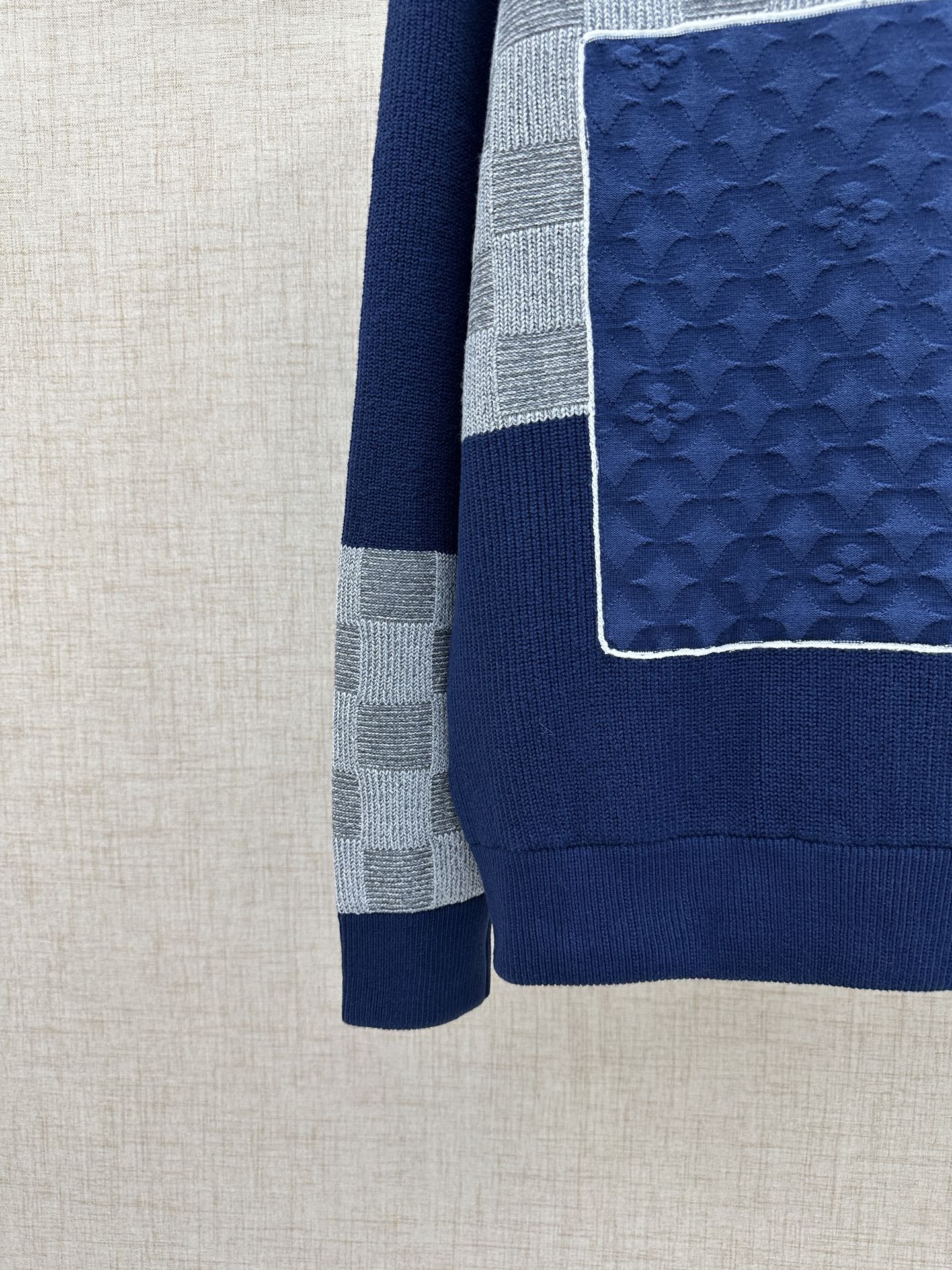 Side view of navy knit sweater jacket with textured blue panel and gray checkered band