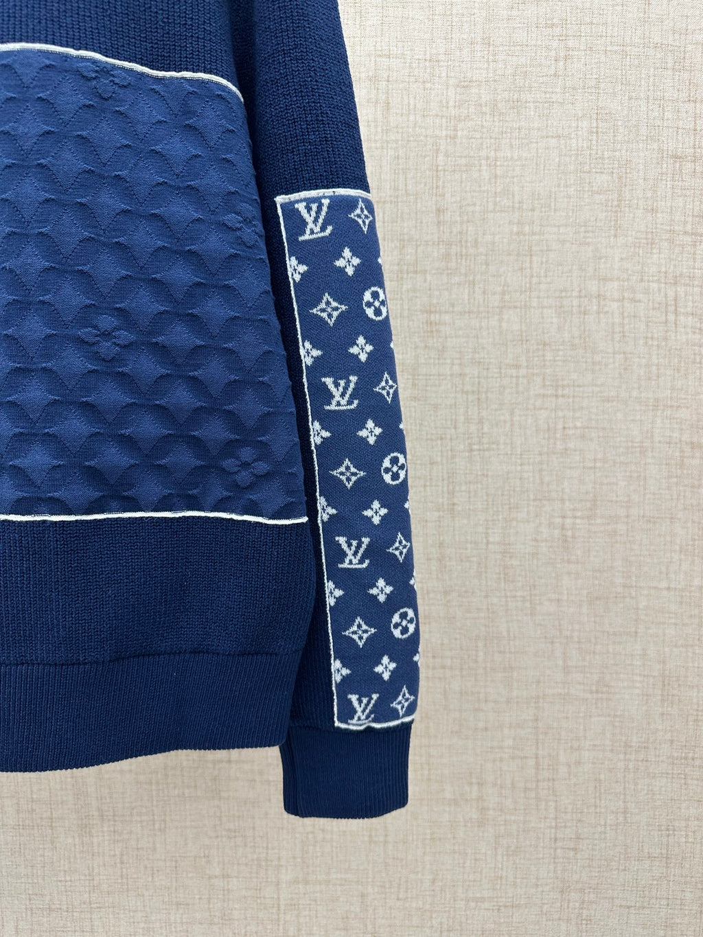 Sleeve cuff on navy knit jacket with logo-pattern fabric and dark ribbed hem